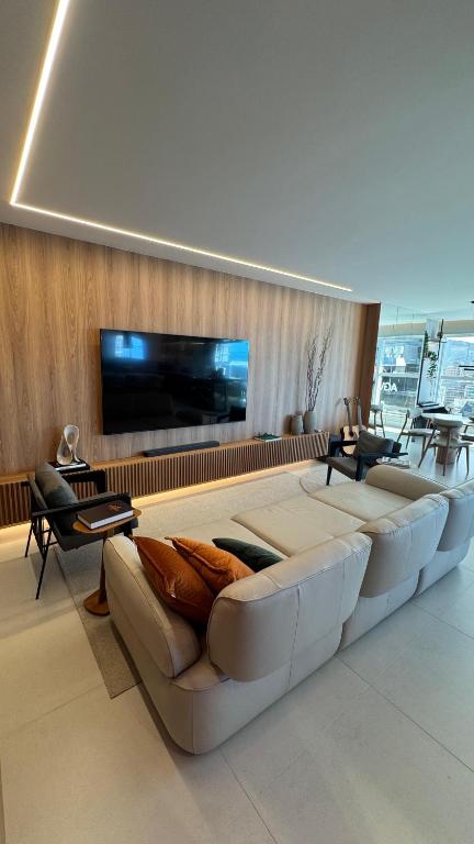 Apt luxo vista mar 160m com jacuzzi e 2 garagens في ايتابيما: غرفة معيشة مع أريكة وتلفزيون بشاشة مسطحة