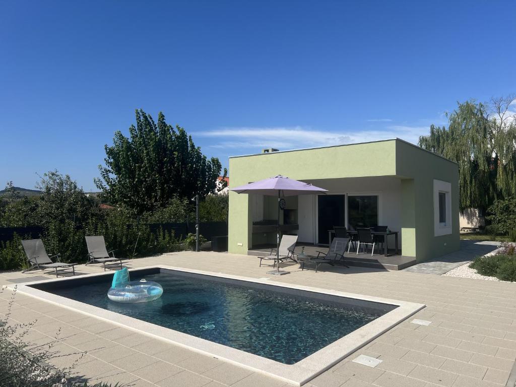 une piscine avec une fontaine en face d'une maison dans l'établissement Villa Ispo Volta, à Posedarje