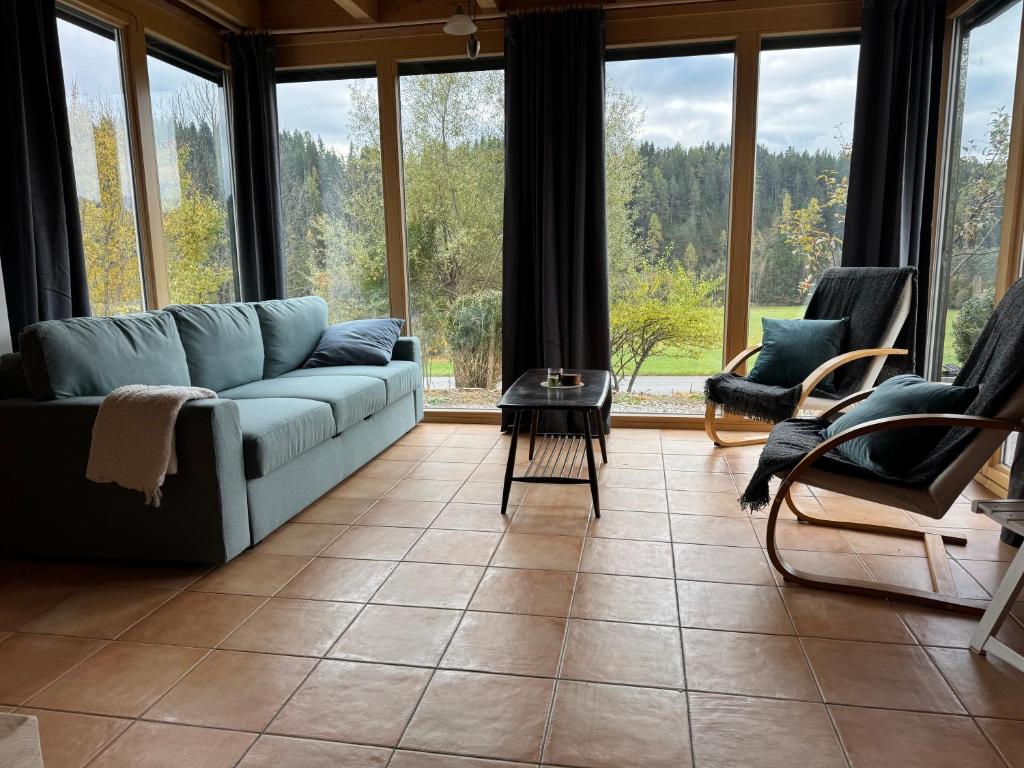a living room with a couch and chairs and windows at Gipfelruhe Ramsau am Dachstein in Ramsau am Dachstein