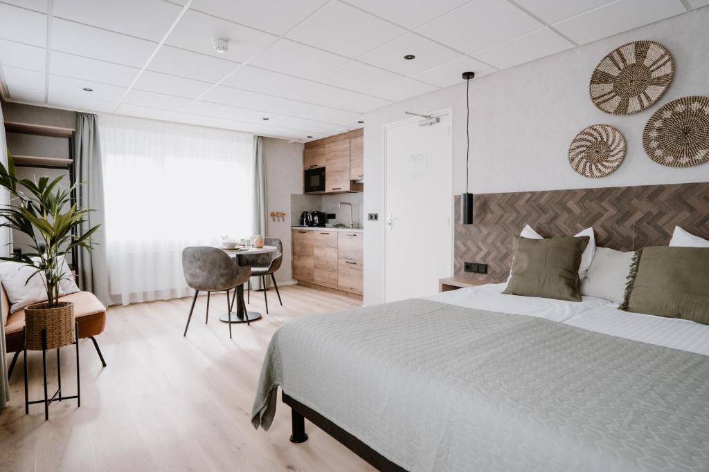 a bedroom with a large bed and a desk at Hotel Kodde in Aagtekerke