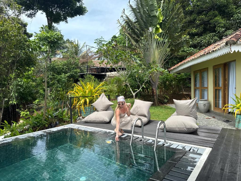 韦利格默Villa Hillcrest Weligama的坐在游泳池旁椅子上的女人