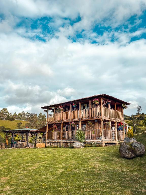 a large wooden house in a field of grass at Hotel - Posada Las Rocas - Guasca Cundinamarca in El Lindero