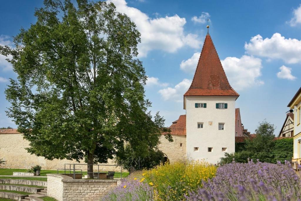 un château avec une tour, un arbre et des fleurs dans l'établissement allio - das turmchalet, à Berching