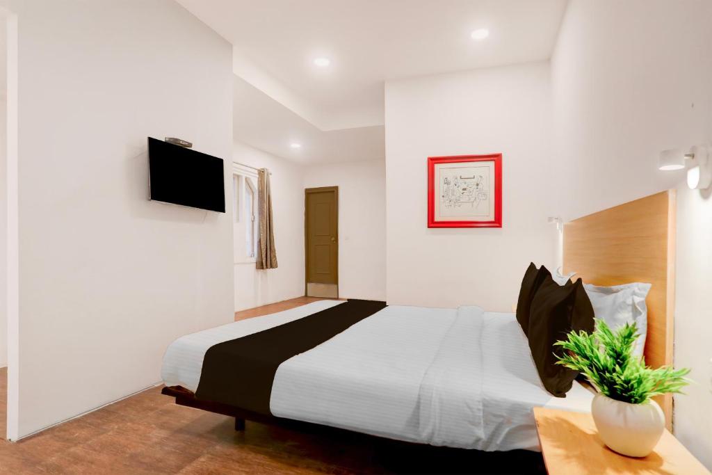 a bedroom with a bed and a tv on a wall at Townhouse Nagpur Junction Formerly Hotel Woodland in Nagpur