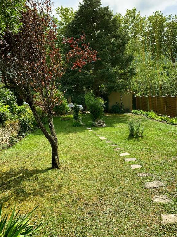 a garden with a tree and a stone path at Le jardin du Griffoul in Nébias