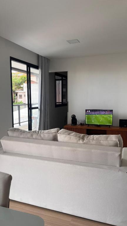 a living room with a white couch and a tv at SouMais Icaraí, Varanda dos Sonhos in Niterói