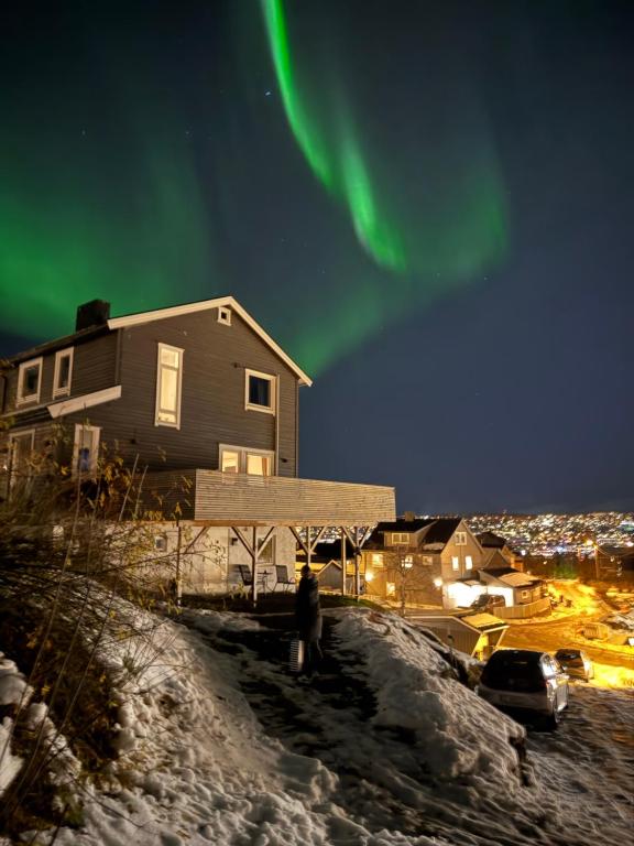 a person standing on a hill near a house under the northern lights at Sentral og koselig leilighet in Tromsø