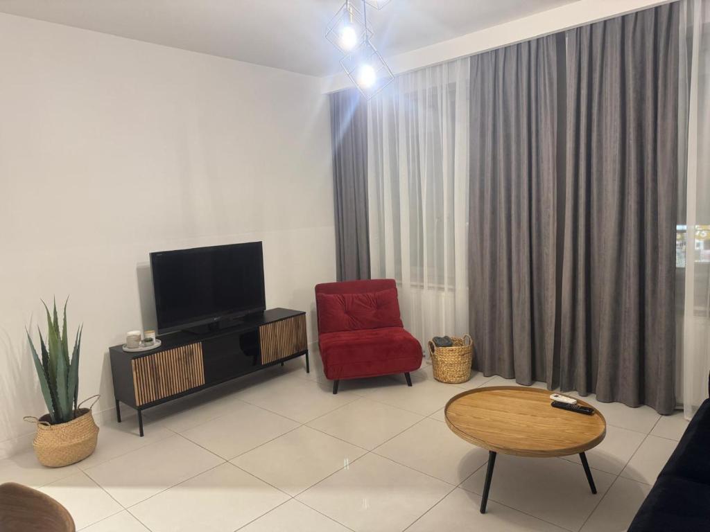 een woonkamer met een rode stoel en een televisie bij Apartament in Skorka