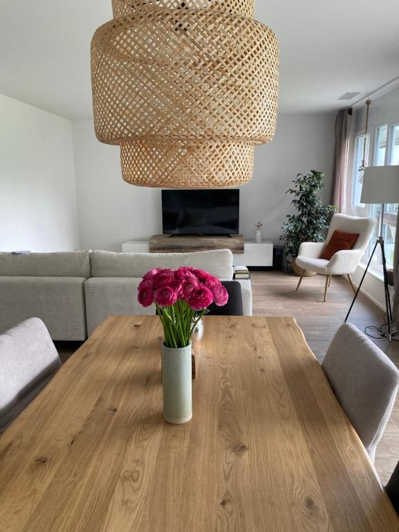 Un jarrón de flores sobre una mesa de madera en una sala de estar. en Comfort Zone, en Lenzburg