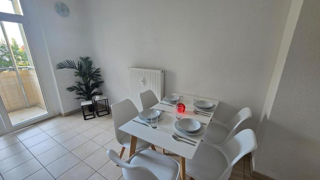 ein weißes Esszimmer mit einem weißen Tisch und Stühlen in der Unterkunft 3-Raum-Wohnung beim Luther in Chemnitz