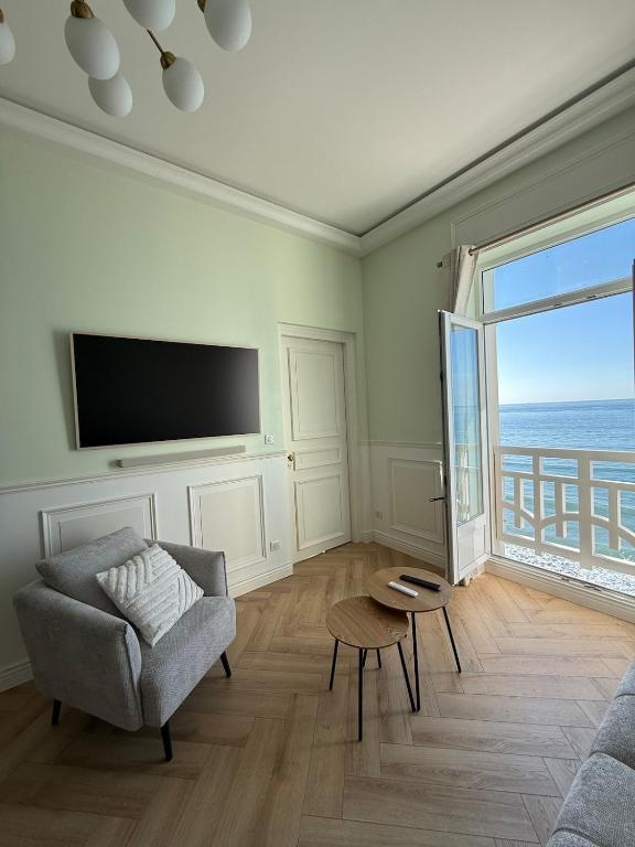 a living room with a couch and a tv and a window at Vue Mer Panoramique - Appartement d'Exception in Wimereux