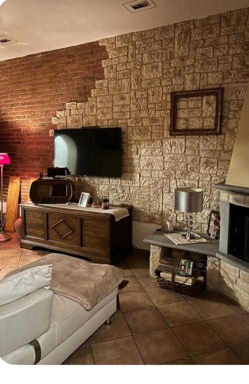 a living room with a brick wall with a tv at Casa Lucy in Ponte Buggianese