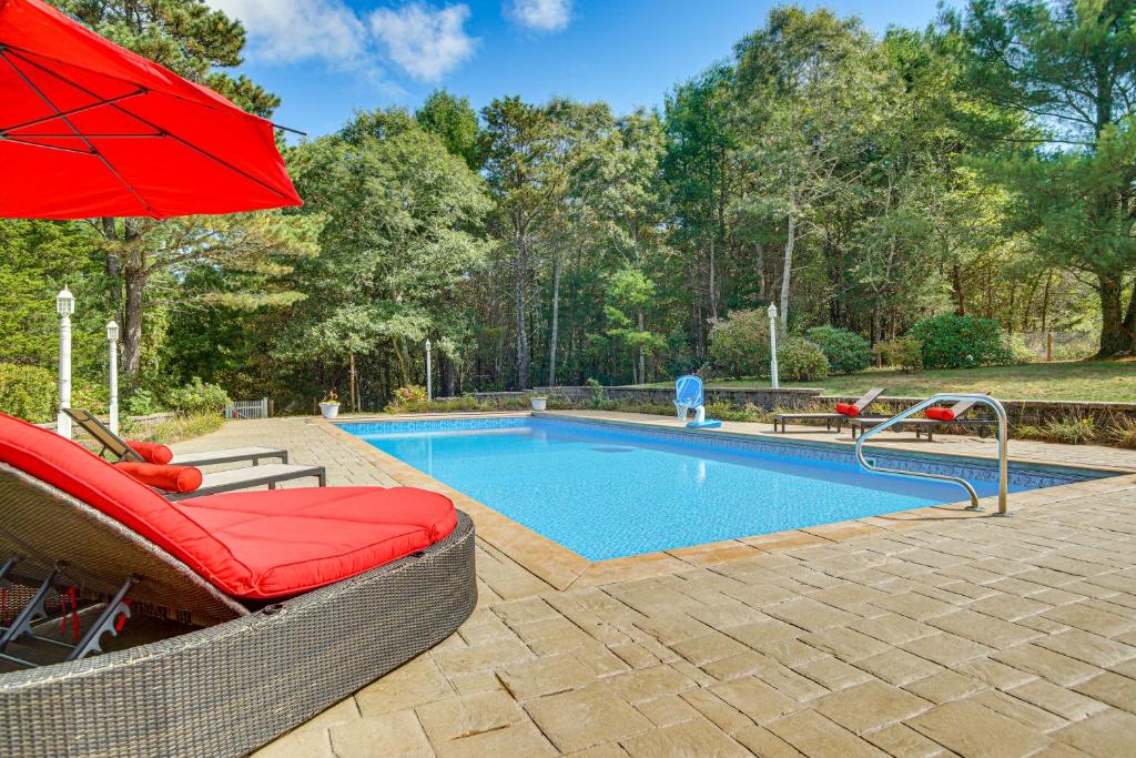 una piscina con una sombrilla roja y algunas sillas y una sombrilla roja en 3 Mi to Megansett Beach Home with Pool and Game Room, en North Falmouth