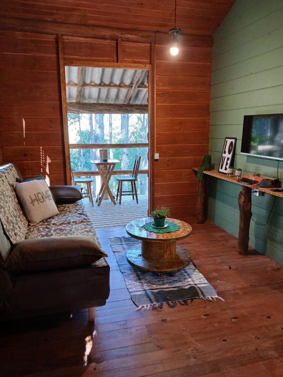 a living room with a couch and a table at Cabana Beija Flor, a nest in nature in Tijucas