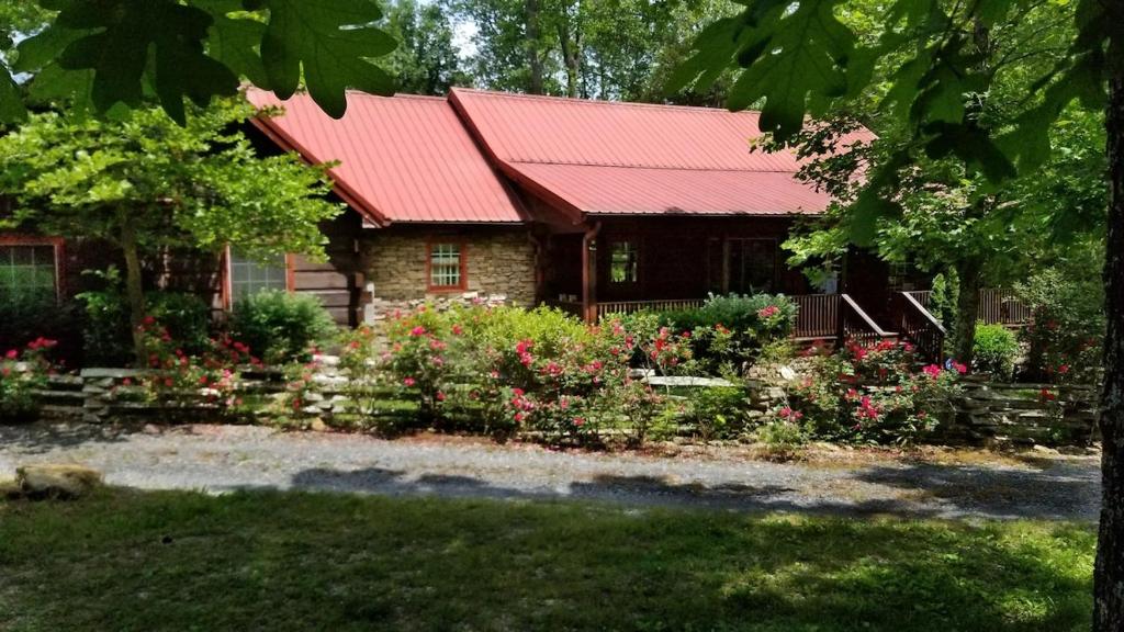 ein Haus mit einem roten Dach und Blumen davor in der Unterkunft Beautiful Secluded Log Cabin in Cleveland