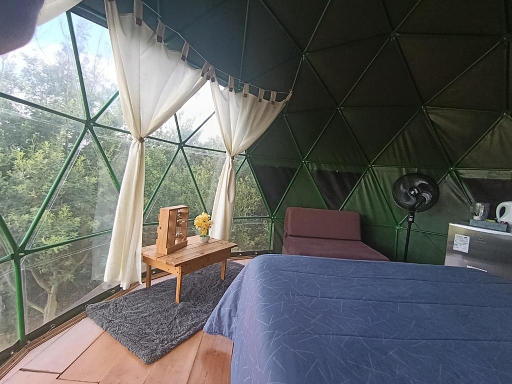 Una habitación con una cama en una tienda de campaña verde. en Glamping El Refugio, en Guatavita