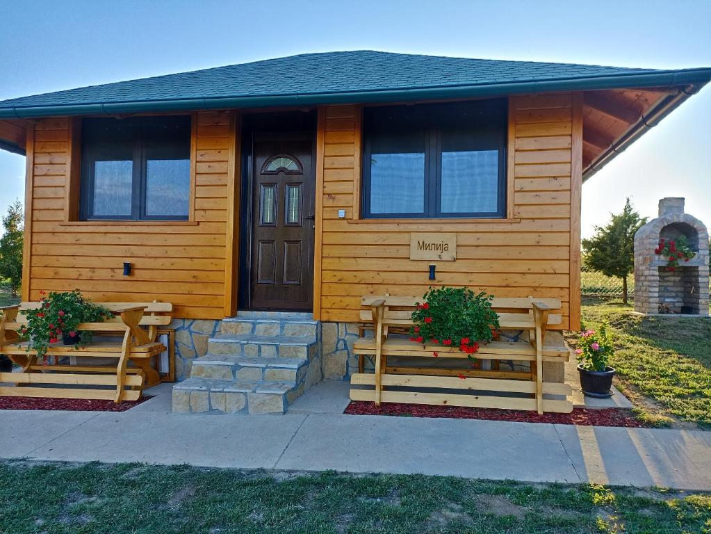 a wooden house with two benches in front of it at Fruškogorske brvnare in Sremski Karlovci