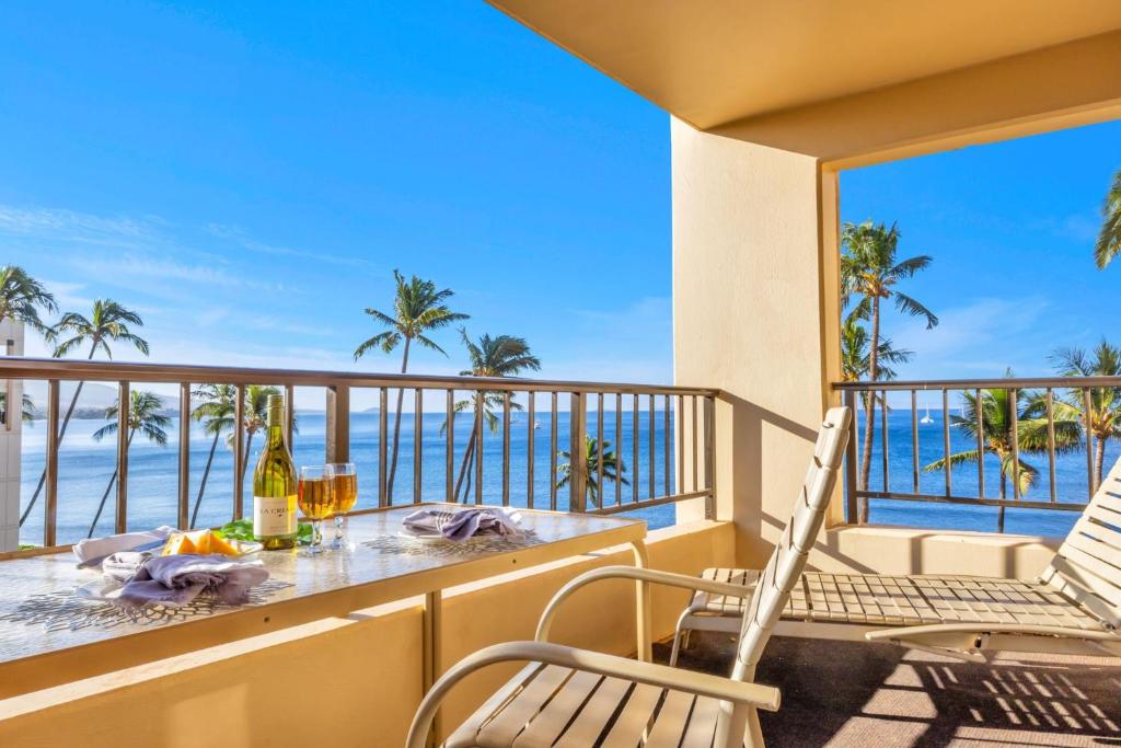 a balcony with a table and chairs and the ocean at Sugar Beach 511 in Kihei