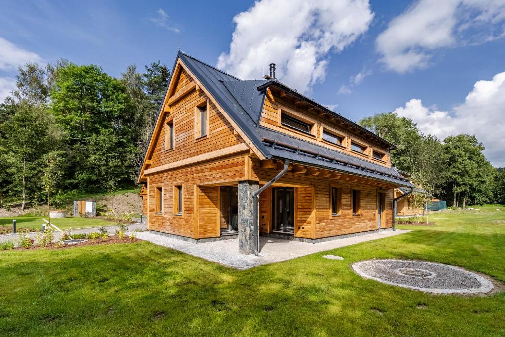 a log house with a black roof on a yard at Vila Sněženka in Horní Planá