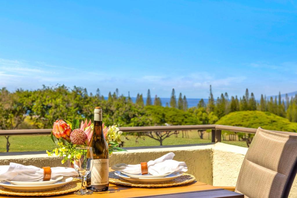 a table with a bottle of wine and plates and flowers at NEW KBM Resorts FREE CAR Kapalua Golf Villas 1-Bedroom Condo with Spacious Lanai and Golf Course Views KGV-18T4 in Kapalua