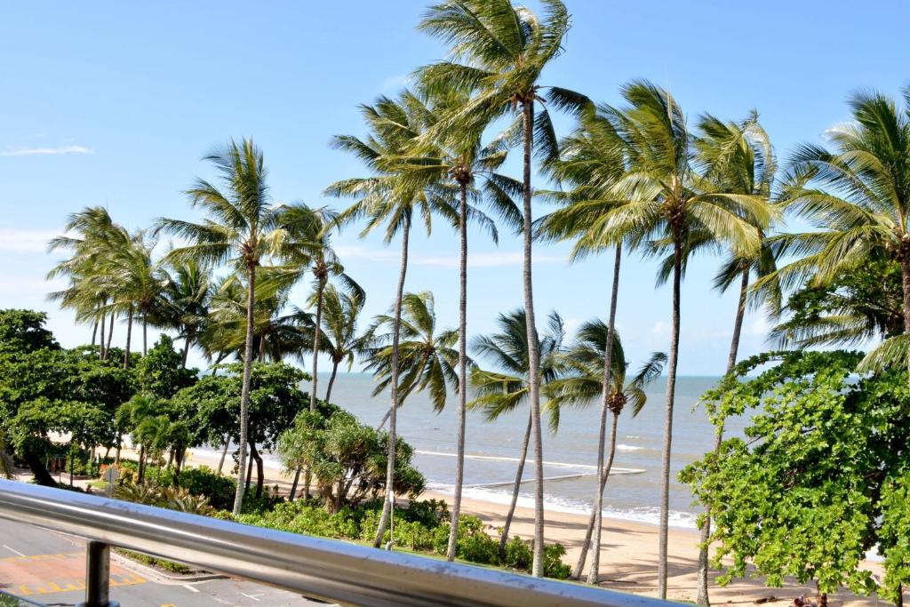 Blick auf einen Strand mit Palmen und das Meer in der Unterkunft Beachfront 3-Bed with Pool & Stunning Ocean Views in Trinity Beach