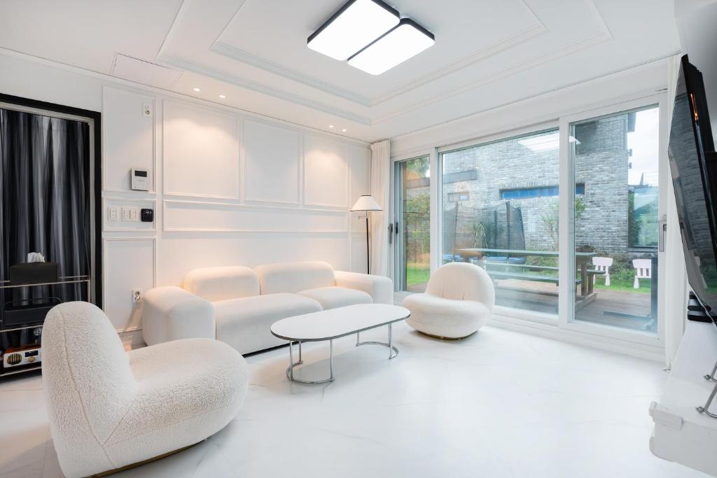 a living room with white furniture and a table and chairs at Domostay in Seogwipo
