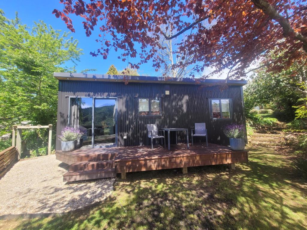 a tiny house with two chairs and a deck at Rural Farmstay in Riwaka