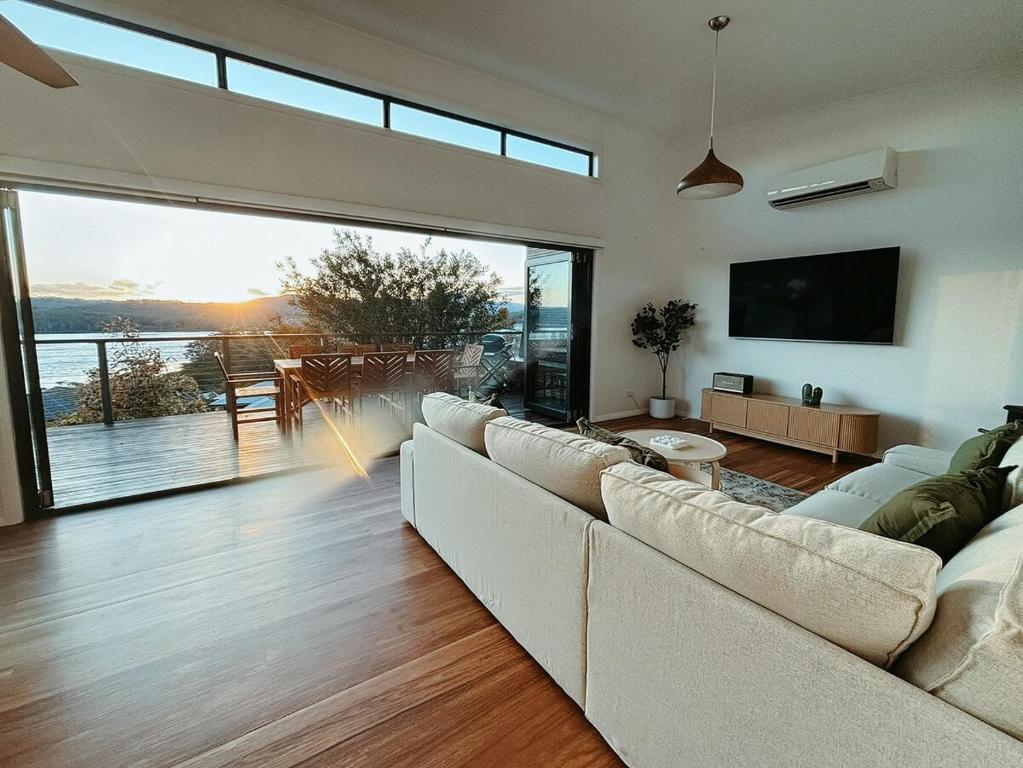 a living room with a white couch and a large window at Snapper Hideaway - Pet Friendly in Merimbula