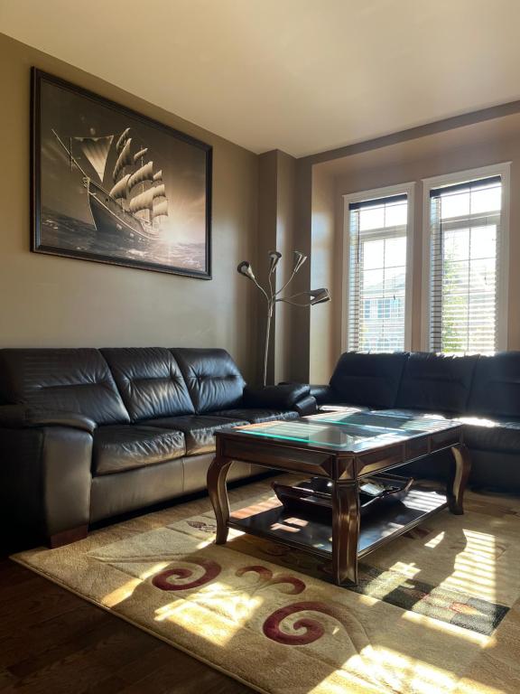 a living room with a leather couch and a coffee table at 3300 SqFt - Modern and Comfort - 3 BDRM Getaway - Relax - Unwind - Explore - Near Toronto Pearson Airport & Toronto Downtown in Brampton