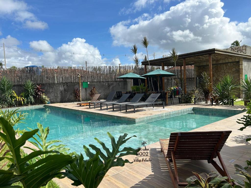 a swimming pool with chairs and umbrellas at Milagres - VIllas Patacho in Pôrto de Pedras