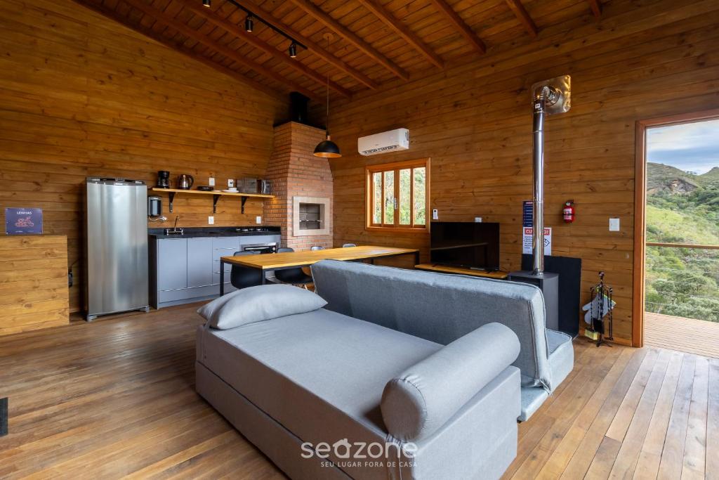 a living room with a couch and a kitchen at Cabana c/ vista e jacuzzi Serra Catarinense VST025 in São Paulo dos Pinhais