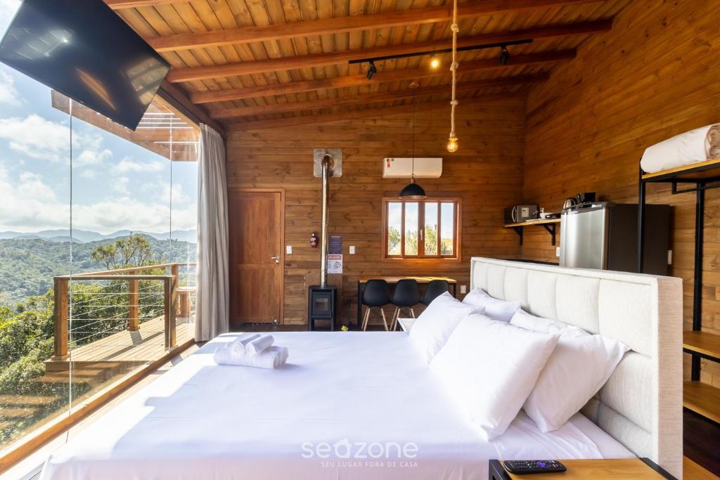 une chambre avec un grand lit blanc et une grande fenêtre dans l'établissement Chalé Charmoso c/ Jacuzzi de Hidromassagem VST024, à São Paulo dos Pinhais