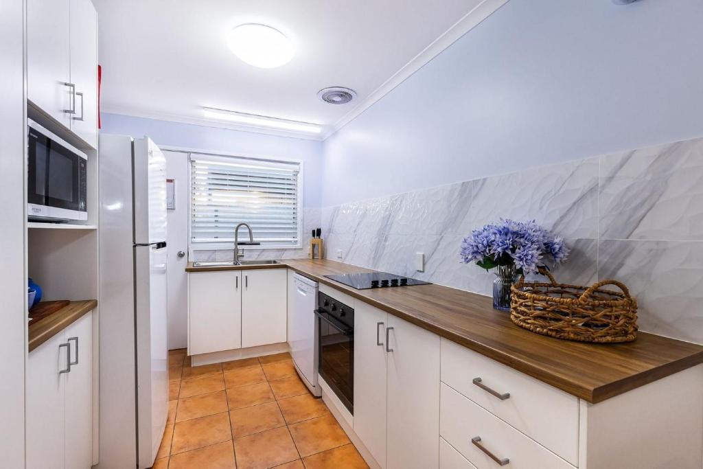 une cuisine avec des armoires blanches et un comptoir en bois dans l'établissement Lakeside Apartments 4, à Merimbula