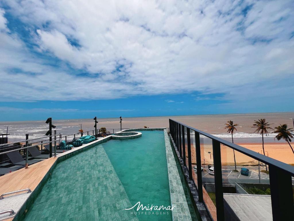 ein Schwimmbad mit Strand im Hintergrund in der Unterkunft Garden Haus Beira-Mar, Jardim Oceania-Miramar Hospedagens in Tambaú