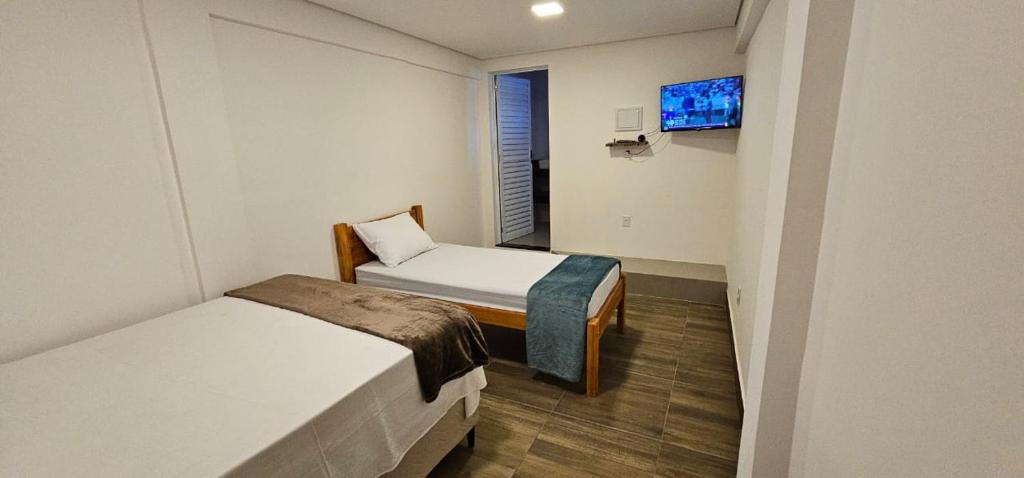a small room with two beds and a television at Dima's in Porto Seguro