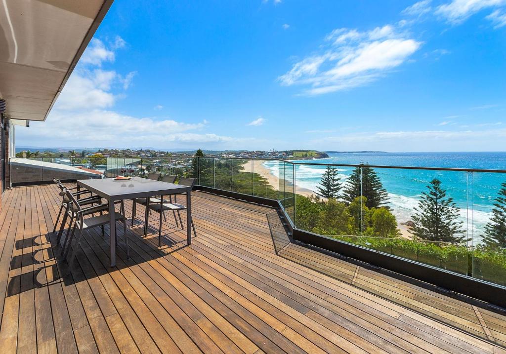 Una terraza de madera con una mesa y sillas en un balcón. en Morning Glow - Wake up to breathtaking views and golden sunrises at this serene coastal retreat., en Bombo