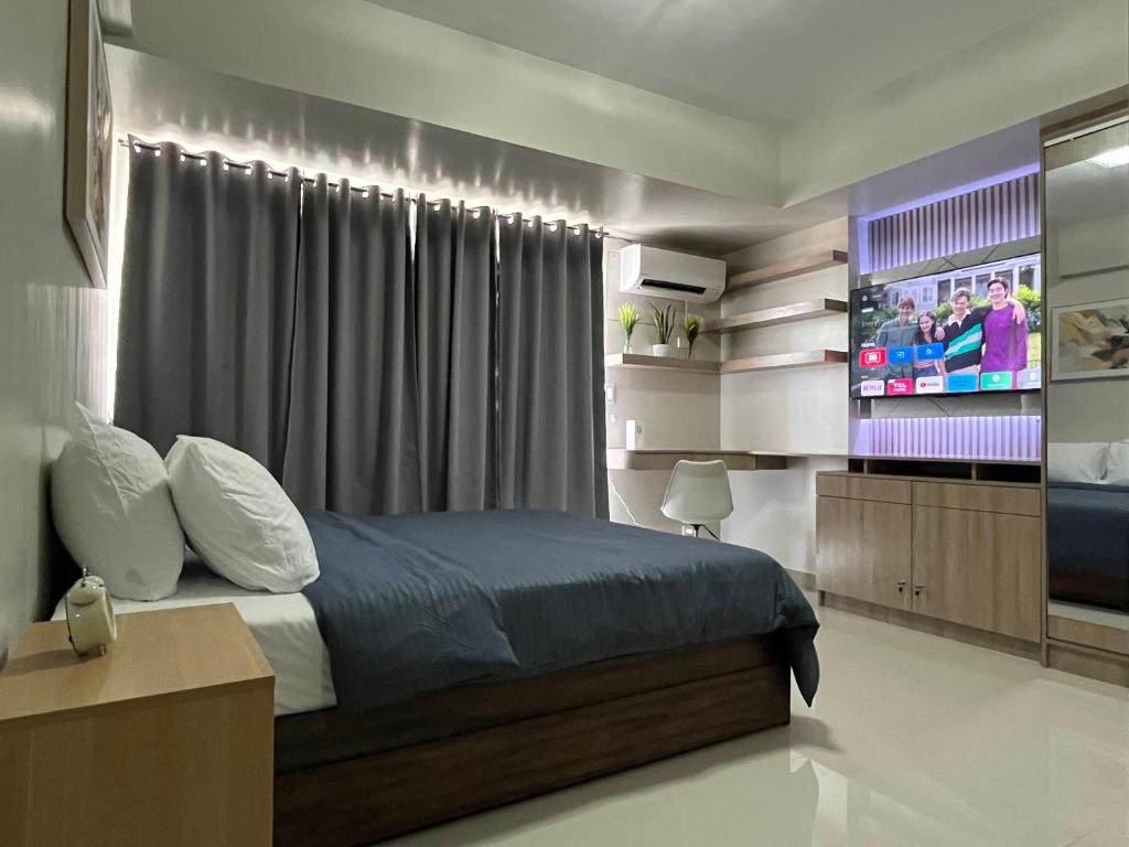 a bedroom with a bed and a flat screen tv at Aspen Suites Condo in Davao City
