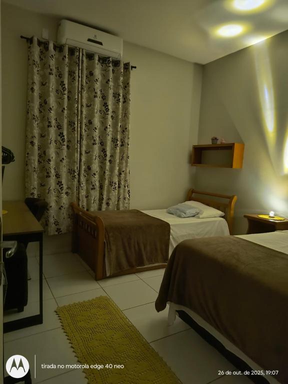 a hotel room with two beds and a window at Casa Serena in Camocim