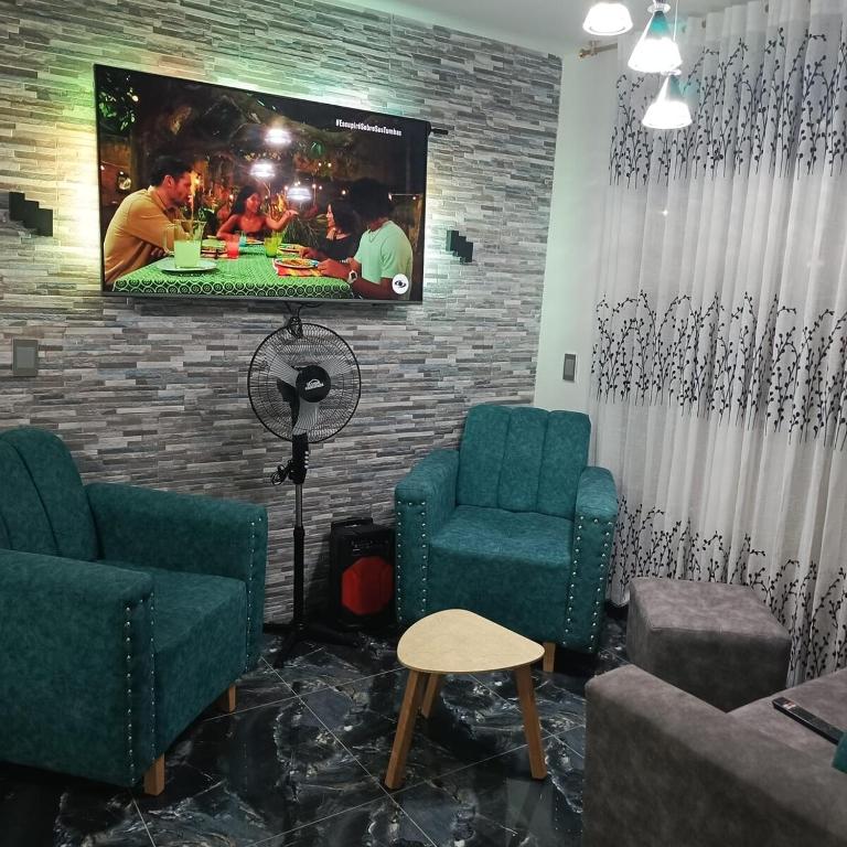 a waiting room with two chairs and a tv on a brick wall at Hogar tranquilo con piscina in Ibagué
