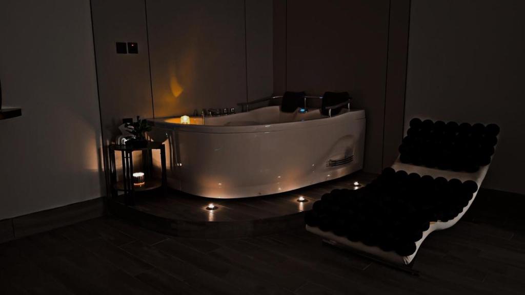 a bathroom with a tub with lights and a chair at غرفة بجاكوزي مع صالة 1 من أرام ريزدنس by ARAM Residence in Aţ Ţuwayr