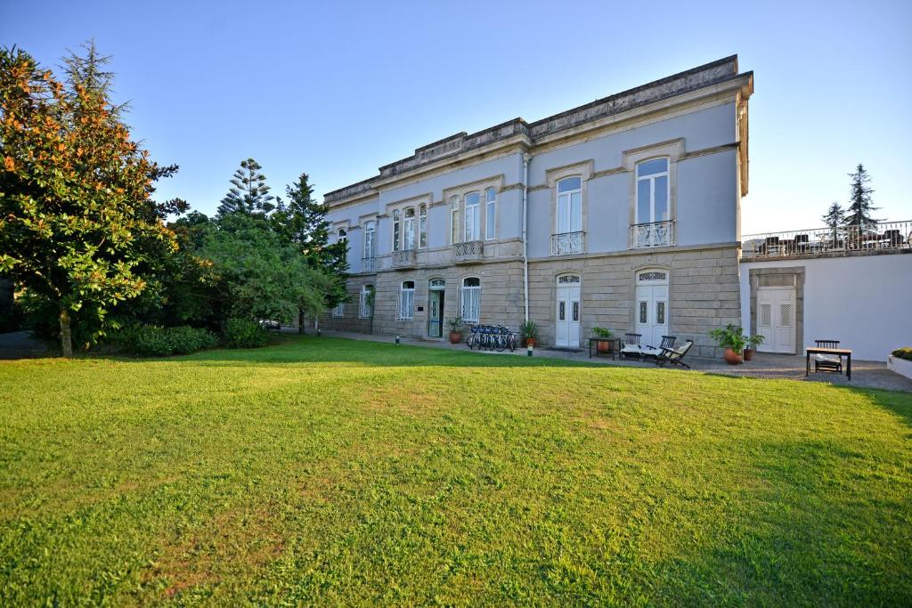 un grand bâtiment avec une cour herbeuse devant lui dans l'établissement Hotel Villa Garden Braga, à Braga