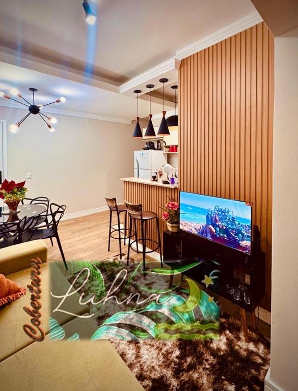 ein Wohnzimmer mit einem TV und einem Esszimmer in der Unterkunft Cobertura LUHNA - 3 Quartos-Ar Condicionado-Vista Cidade-6 Pessoas in Salto