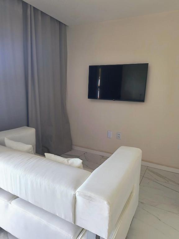a living room with a white couch and a flat screen tv at Espaço Zen in Camaçari