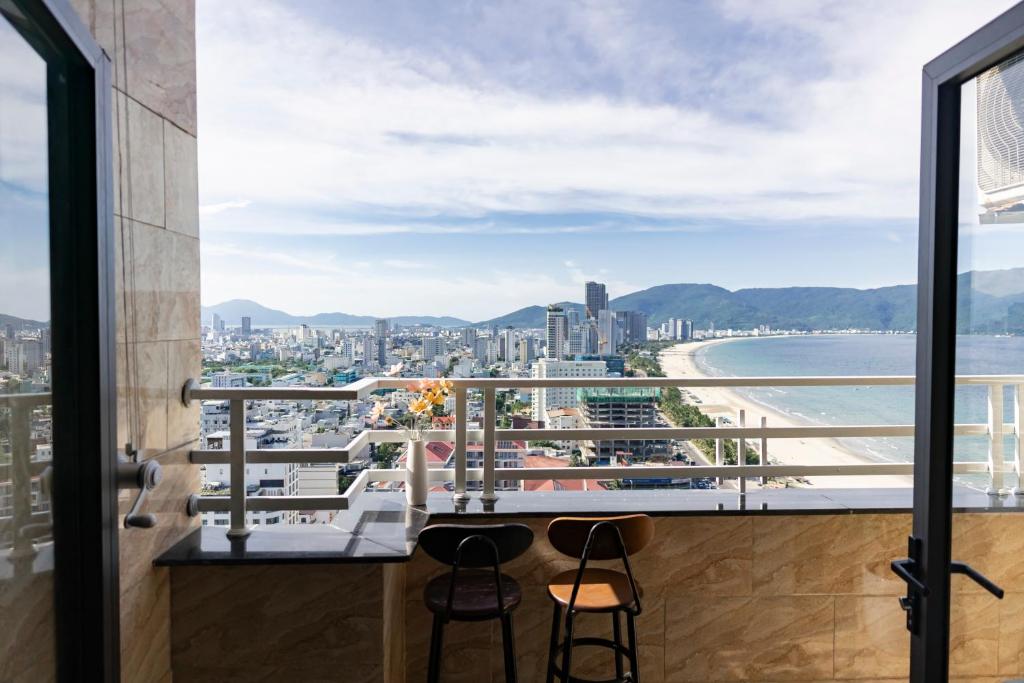 a balcony with two chairs and a view of a city at 2BR Apartment by My Khe Beach - Beachfront escape in Da Nang
