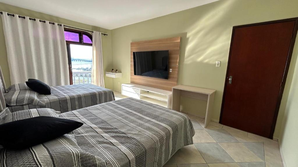a hotel room with two beds and a flat screen tv at Casa Mirante do Mar Floripa in Florianópolis
