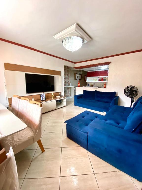 ein Wohnzimmer mit einem blauen Sofa und einem Fernseher in der Unterkunft Casa Aconchegante no Coração de Arraial - Com Churrasqueira Privativa in Arraial do Cabo