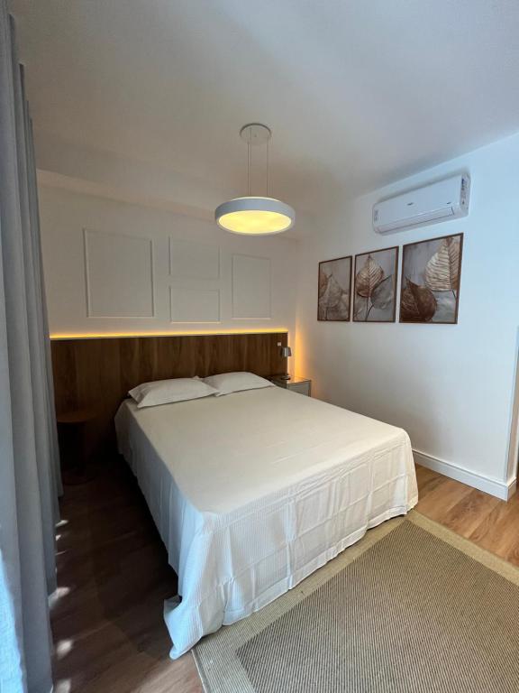 - une chambre avec un lit blanc et une lumière dans l'établissement Giardino, Studio Moderno Aconchegante e Tranquilo, à Guarulhos