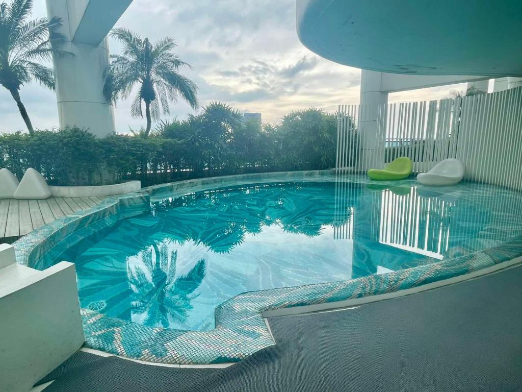 a large swimming pool in a building with palm trees at Acqua Private Residences Livingstone Tower in Sampong