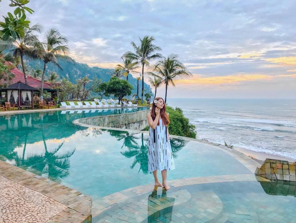 une femme debout à côté d'une piscine au bord de l'océan dans l'établissement Queen of the South Beach Resort, à Yogyakarta