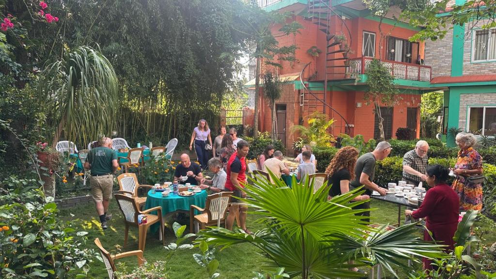 a group of people standing in a garden with tables at New Pokhara Lodge - Pokhara Lakeside in Pokhara